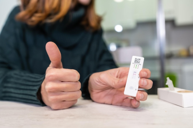 Mujer muestra un test rápido de antígenos en su casa