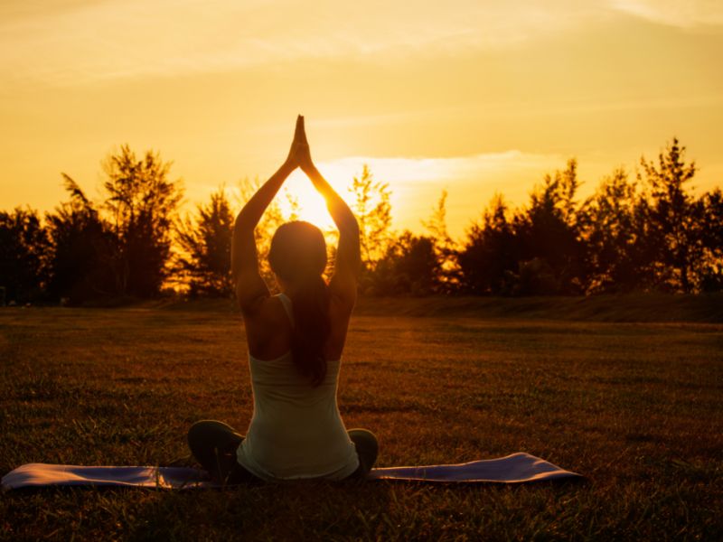 Mujer practicando yoga al aire libre durante el atardecer