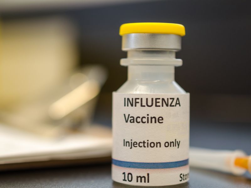 Frasco de vacuna contra la influenza junto a una jeringa