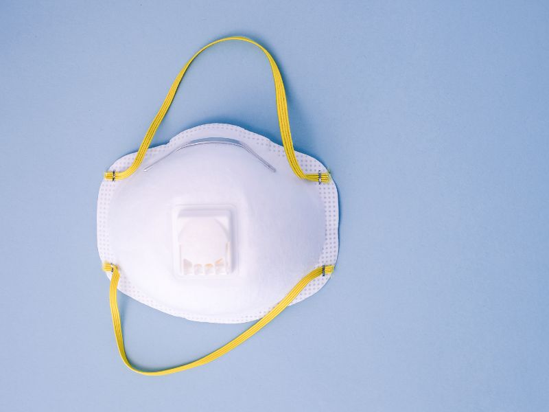 Mascarilla desechable con válvula de filtración sobre fondo azul