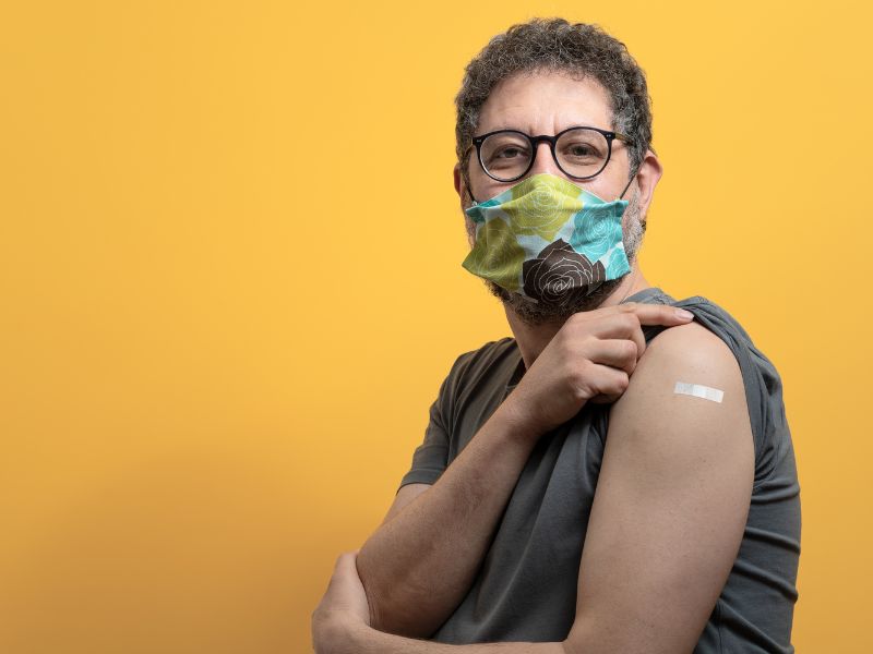 hombre muestra su brazo con la vacuna influenza